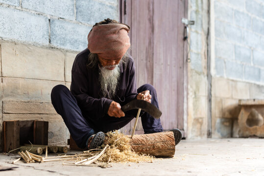 Senior Thai villager carving bamboo at rural home