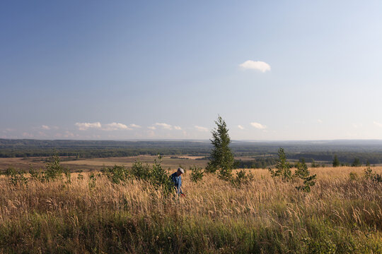 Man walking through tall golden grass in wide valley
