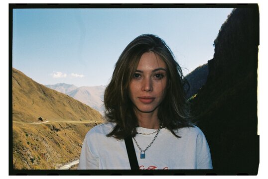 Young woman standing amidst a mountainous landscape. Film, flashlight