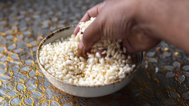 Hand Touching Puffed Rice (Muri) in Clay Bowl &ndash; Close-Up Natural Food Texture Shot