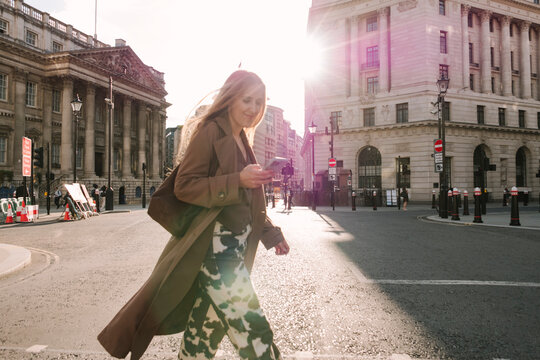 Woman crossing street with phone