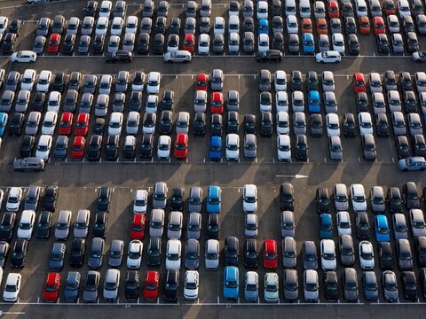 Aerial view of a sea of orderly parked cars, where vibrant reds, whites, blues, and blacks create a stunning mosaic of automotive colors, Civitavecchia, Lazio, Italy.