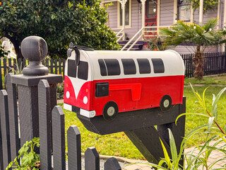 Red and white retro van shaped mailbox in suburban neighborhood, creative home exterior design