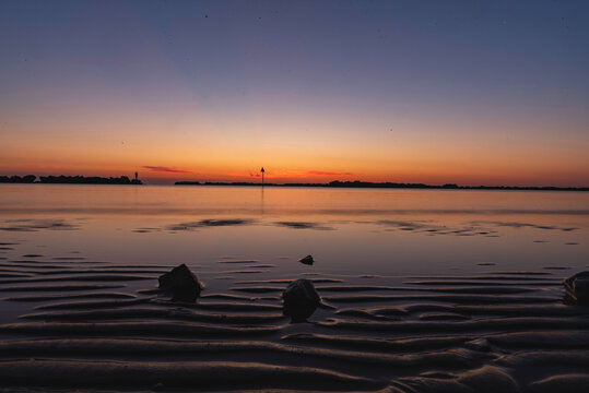 Rimini, Italy-August,22,2020:Colorful sunrise over calm sea with silouette rocks