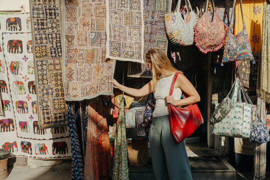 Woman Browsing Handcrafted Bags and Textiles in a Colorful Market