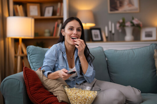 Woman enjoying evening watching tv with popcorn at home