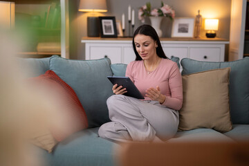 Obraz premium Woman making video call using tablet on sofa