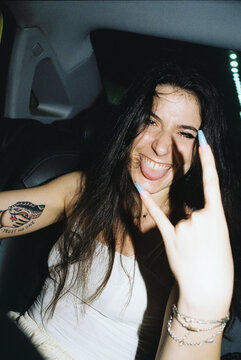 A smiling woman in a car giving the horns 