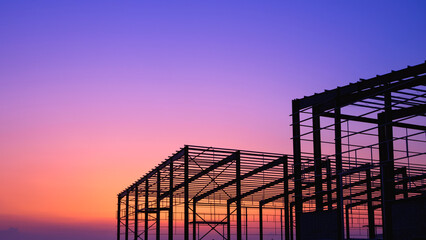 Naklejka premium Silhouette steel structure of 2 industrial warehouse factory buildings framework in construction site against colorful twilight sky background, perspective side view with copy space