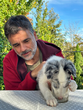 Man Watching Puppy Drink From Glass