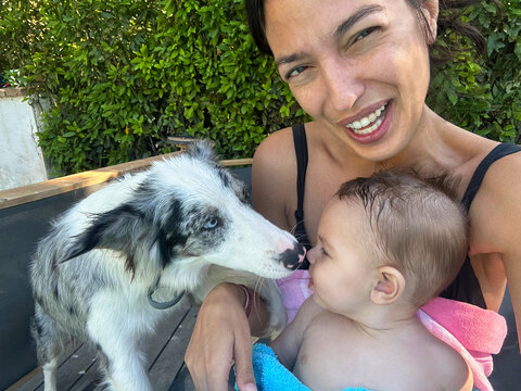 Selfie of a Smiling Woman Holding Baby and dog