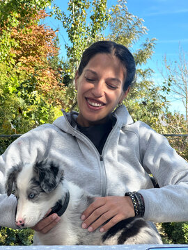 Woman Smiling While Holding Blue Merle Border Collie Puppy