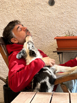 Man Resting With Puppy On Chest In Chair