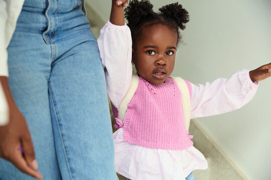 Little girl walking down stairs holding adult&rsquo;s hand