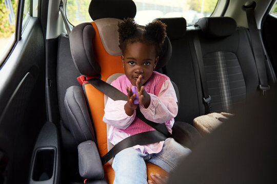 Little girl sitting in car seat clapping hands