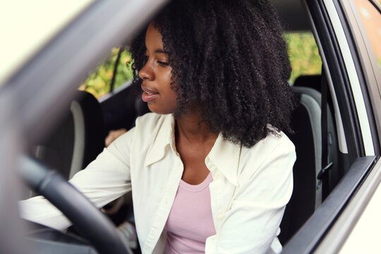 Woman sitting in car adjusting controls