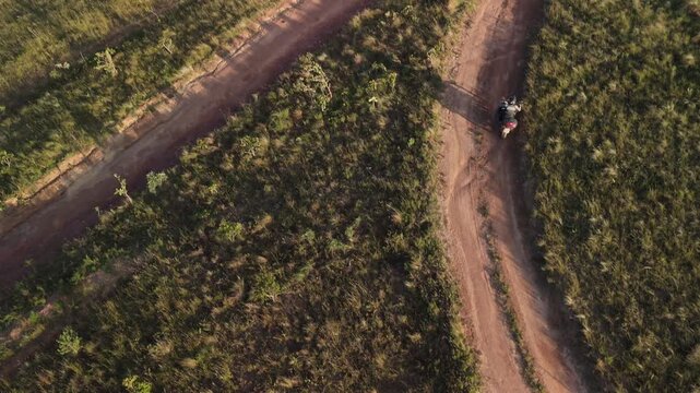 Vista a&eacute;rea de uma motocicleta em uma estrada de terra deserta.