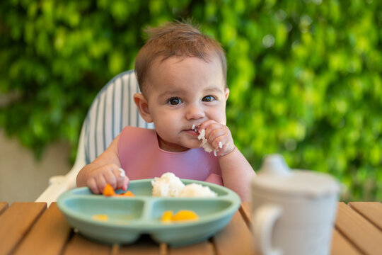 Baby Eating Rice Outdoors With Bib