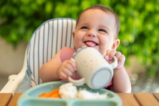Happy Baby Holding Cup And Smiling Outdoors