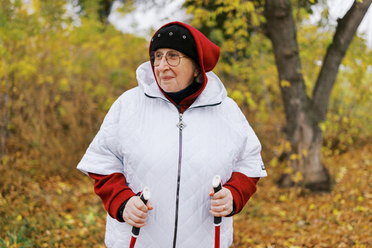 Elderly Woman Enjoying a Brisk Walk in Autumn Park