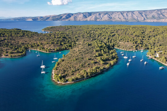 Aerial view of boats resting in the turquoise Jack Sparrow Bay, surrounded by lush greenery near Stari Grad, Hvar island, Dalmatian Coast, Croatia.