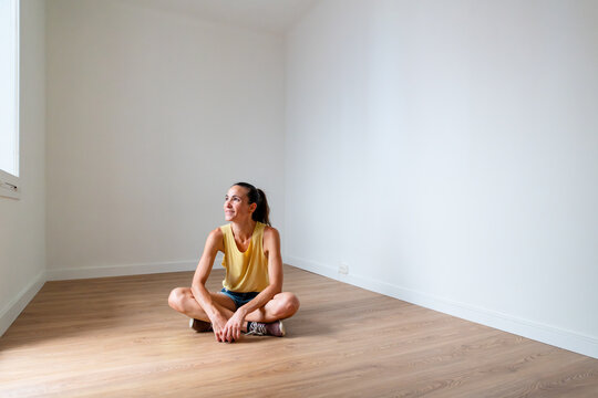 Happy woman sitting on empty apartment
