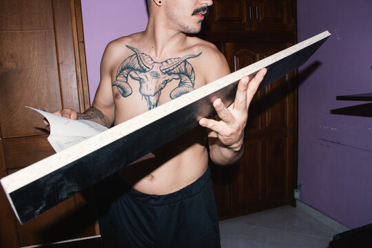 Man Studies Assembly Instructions While Building Furniture