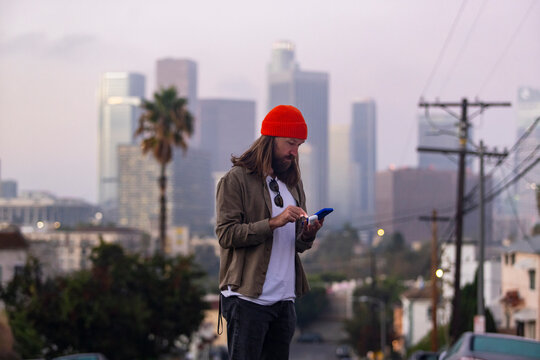 Man texting on  mobile phone Los Angeles city skyline 