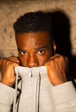 Young Man Hiding Face in Hooded Jacket in Urban Setting