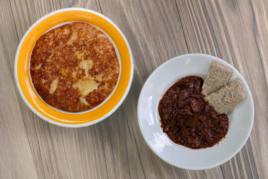 A hearty plate of traditional Friulian frico paired with beef gulash and soft polenta, typical of mountain cuisine.