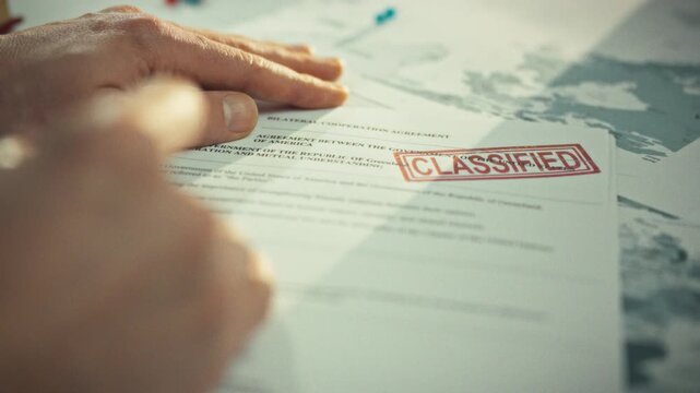 A government official's hands rest on paper documents as he carefully studies a confidential document next to a world map illustrating administrative tasks. The documents are stamped confidential