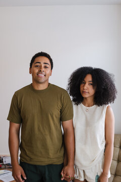 Candid friends stand side by side, smiling in a light, casual sc