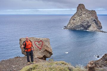 Fototapeta premium Hiker posing by heart rock at Roque de Anaga