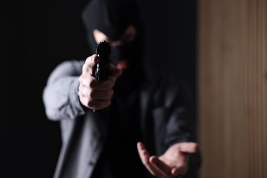 Dangerous criminal holding gun indoors, selective focus. Armed robbery