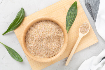 Psyllium husk powder with fresh leaves on concrete background, top view