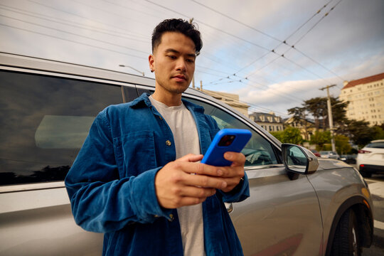 Portrait of a man send texts near his car