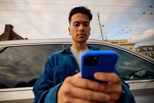 Man sends texts by his car.