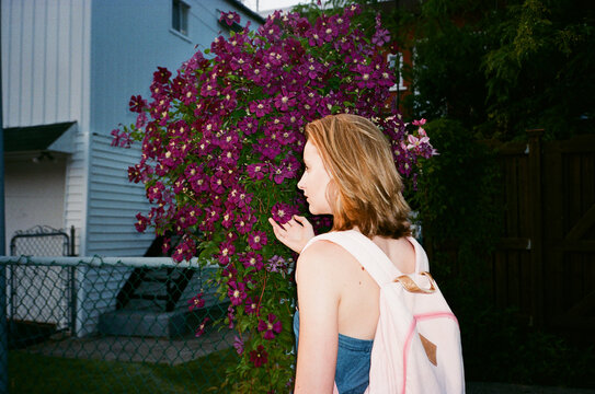 Young Woman Admiring Purple Flowers in Urban Garden