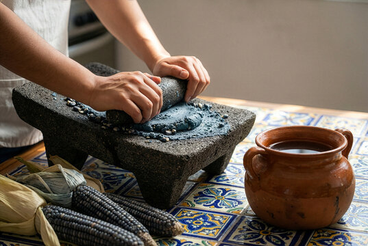 Grinding blue corn on a traditional stone metate for Mexican tortillas.