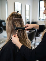 Fototapeta premium Hair styling process at a salon with a stylist using a flat iron