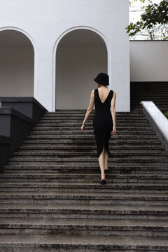 The girl walking up the stairs moving to the white archs.