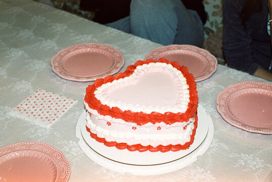 Heart-shaped pink and red cake on decorated table  

