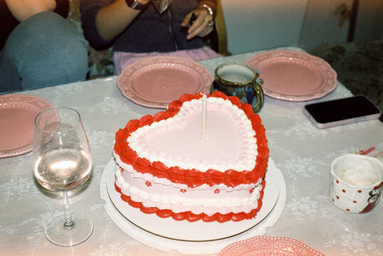 Heart-shaped birthday cake with candle on decorated table  


