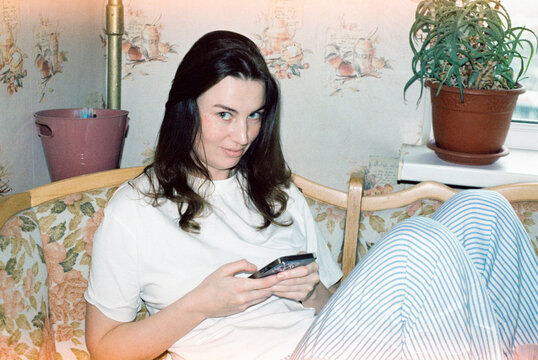 Woman sitting on floral couch using phone  
