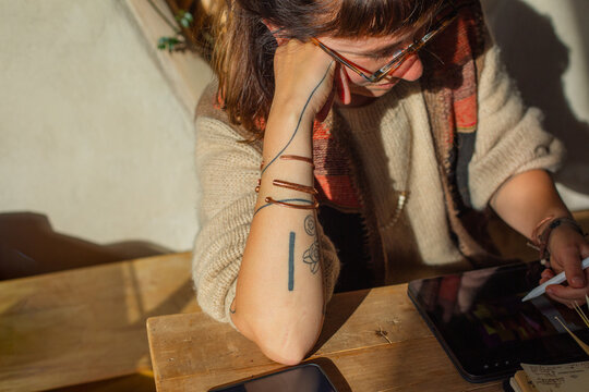 Woman Working on Tablet with Stylus in Warm Light