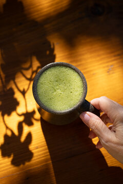 Drinking matcha latte drink on sunlit table 