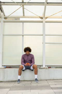  Portrait black man sits and text cell phone outdoors 