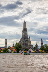 Naklejka premium Panorama of the Wat Arun temple complex in Bangkok, Thailand, taken from across the Chao Phraya River. The central feature is the massive, towering Prang, surrounded by four smaller satellite prangs. 