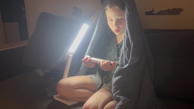 Video: Home reading, a child reading a book under a lamp at night