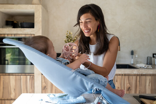Mother Laughing With Baby Playing In Kitchen Bouncer